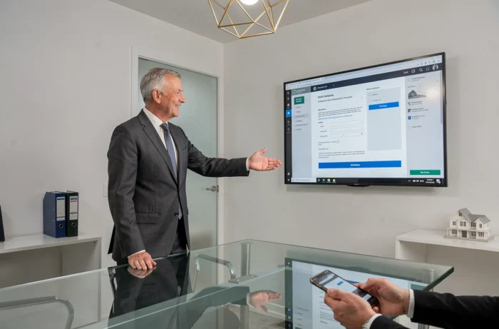 Agent immobilier présentant un processus de signature électronique sur une plateforme immobilière numérique en salle de réunion